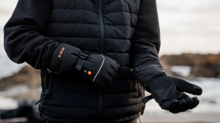 The Best Heated Gloves, Tested and Reviewed Person wearing black ORORO heated gloves and puffer jacket outdoors in cold weather.