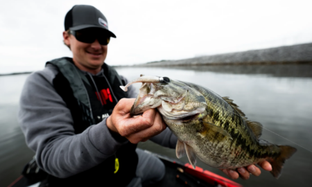 Angler holding a large bass fish caught with a lure on a lake