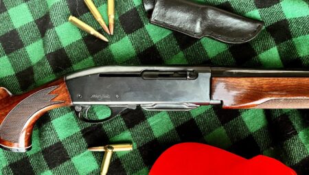 Remington semi-automatic rifle with ammunition and leather holster on plaid fabric background