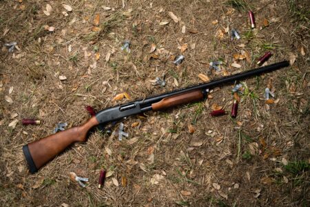 Remington 870 Express Shotgun: Tested and Reviewed Pump-action shotgun with spent shells on autumn leaf-covered ground outdoors