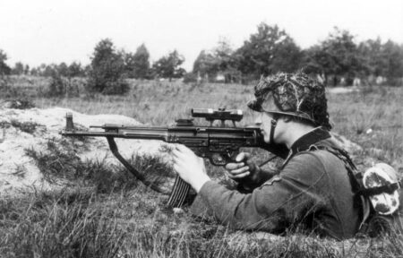 The 17 Most Innovative Military Firearms Ever Soldier in camouflage helmet aiming assault rifle in prone position outdoors