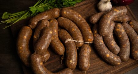 How to Make Venison Sausage Homemade artisan sausages on wooden cutting board with fresh parsley and garlic