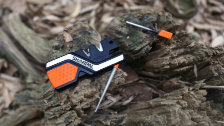 Sharpal portable knife sharpener with diamond rod resting on rustic wood outdoor