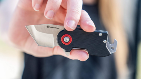 Smith & Wesson folding pocket knife with black G10 handle held in hand