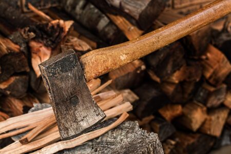 Rusty vintage axe resting on a pile of chopped firewood logs