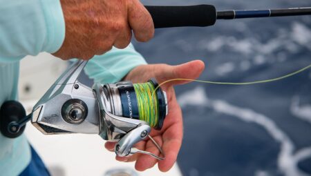 How to Spool a Spinning Reel—an Easy Step-By-Step Guide Angler holding Shimano Saragosa spinning reel with braided fishing line on boat