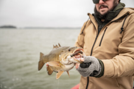 7 Ways to Rig a Stick Bait Fisherman holding a freshly caught largemouth bass with lure in its mouth
