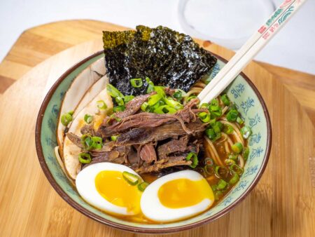 Bowl of beef ramen with soft-boiled egg, nori, and green onions.