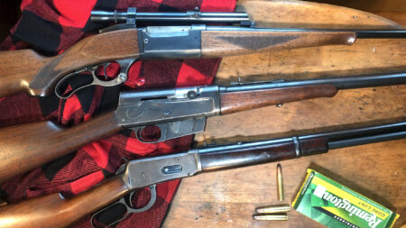 Three vintage lever-action rifles displayed on wooden table with Remington Core-Lokt ammunition.