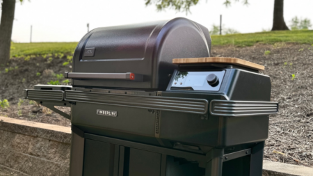 Traeger Timberline pellet grill with digital controls and wood cutting board shelf outdoors