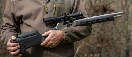 Marlin 1895 Trapper Magpul Rifle Review—Expert Tested Person holding a scoped lever-action rifle with modern tactical stock outdoors.