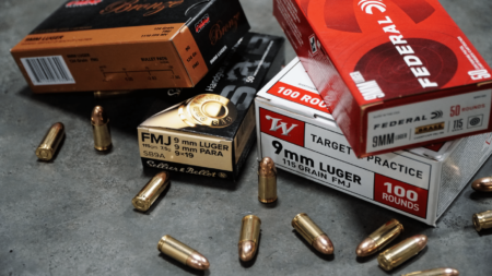 Various 9mm Luger FMJ ammunition boxes and loose rounds on gray surface