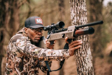 Hunter in camouflage aiming Umarex Gauntlet 2 air rifle in forest setting