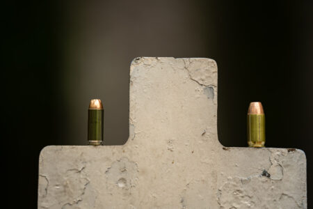 Two copper-tipped bullets balanced on top of a worn concrete cross shape