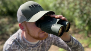 Man in camouflage using Vortex binoculars outdoors while hunting or birdwatching