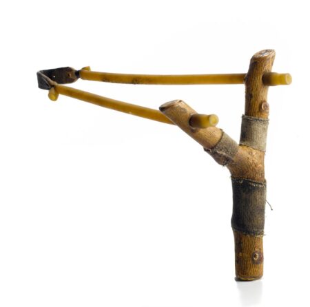 Handmade wooden slingshot with elastic bands and leather pouch on white background