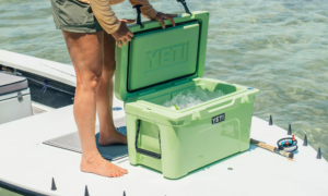 Person opening green YETI Tundra cooler filled with ice on a fishing boat.