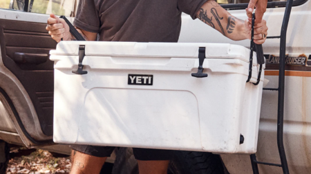The Best Yeti Coolers of 2025, Tested and Reviewed Person lifting white YETI Tundra cooler from Toyota Land Cruiser outdoors.