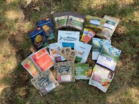 Collection of outdoor backpacking freeze-dried meal packages from brands like Patagonia and Farm to Summit.