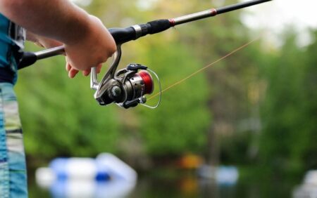 The Best Fishing Reels for Any Type of Angler Child holding fishing rod with spinning reel outdoors near water