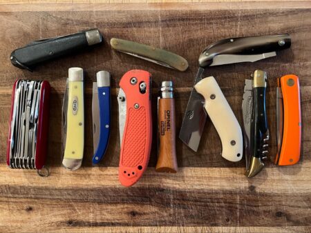 The 12 Best Pocket Knives, According to Our Editors Collection of various folding pocket knives displayed on wooden surface including Opinel and Case brands.