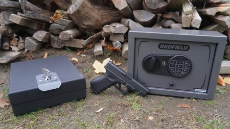 Redfield gun safe and Steelhead lockbox with handgun on ground outdoors