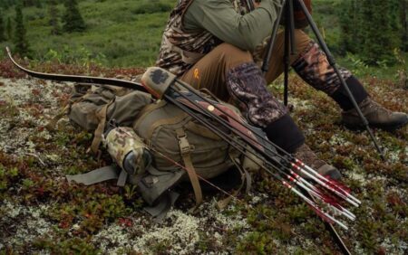 The 7 Best Recurve Bows of 2024 Bowhunter in camouflage gear sitting outdoors with recurve bow and arrows on tundra