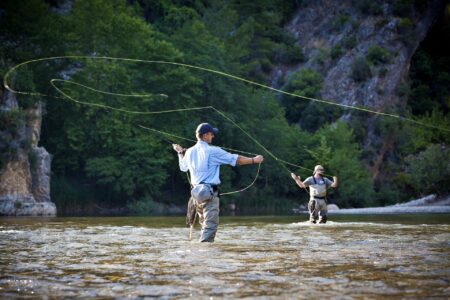 The 6 Best Fly Reels of 2024 Two fly fishermen wading in a scenic river casting fishing lines outdoors.
