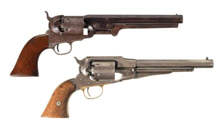 Two antique Civil War era percussion cap revolvers with wooden grips displayed on white background