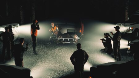 Hunters gathered around a deer in truck bed at night in video game scene