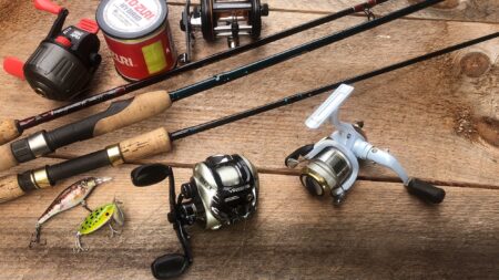 Types of Reels: Which Is Right for Your Next Fishing Trip? Fishing rods, reels, lures, and Yo-Zuri fishing line on wooden surface.
