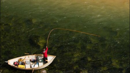 A fly fisherman casts on a muddy river.