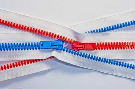 Two colorful red and blue zippers crossing each other on white background