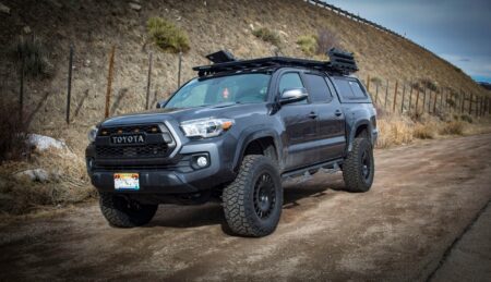 Building My Ultimate Hunting and Fishing Truck Dark gray lifted Toyota Tacoma pickup truck with roof rack on dirt road