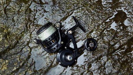 Reel Tough: My Invincible Zeebaas ZX Black spinning fishing reel with green line on wet rocky surface