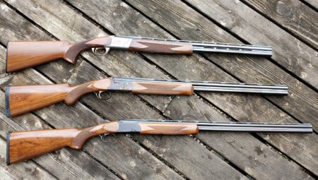 The Long and Short of Shotgun Barrels: 6 Things You Need to Know Three over-under shotguns with wooden stocks displayed on weathered wooden deck
