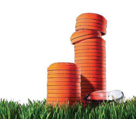 Stacked orange clay shooting targets on green grass with safety glasses