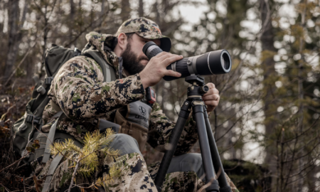 Cabela’s Biggest Sale of the Year Has Begun—Here’s What’s Worth Grabbing Hunter in camouflage using Leupold spotting scope on tripod in forest