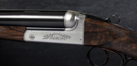 Ornate engraved Heym double-barrel shotgun with walnut stock and silver receiver