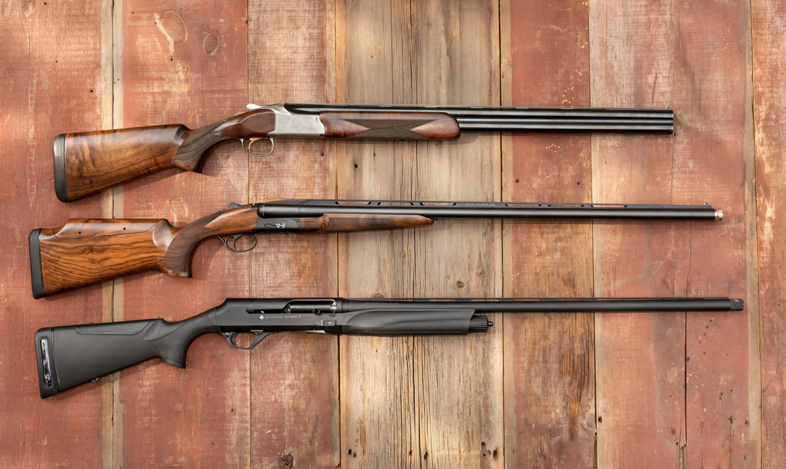 Three of the best shotguns of 2025 resting on barn boards.