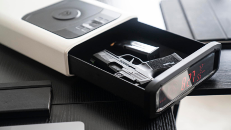 Sig Sauer pistol stored inside an open biometric bedside gun safe with clock display