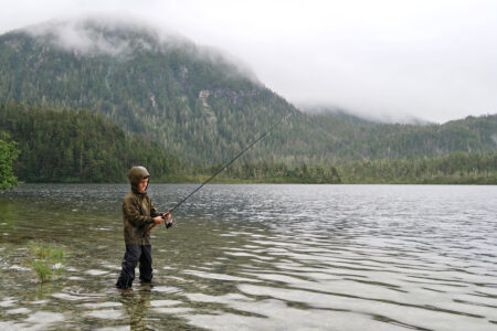 Trump Administration Moves to Revoke Roadless Rule Protections on Millions of Acres of Public Land Child fishing in mountain lake on cloudy day wearing rain jacket