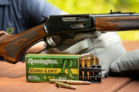 A Marlin 336 rifle and Remington 30-30 ammo on a shooting bench.