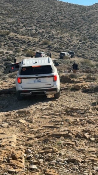 A white SUV climbs up a rocky hill in Death Valley.