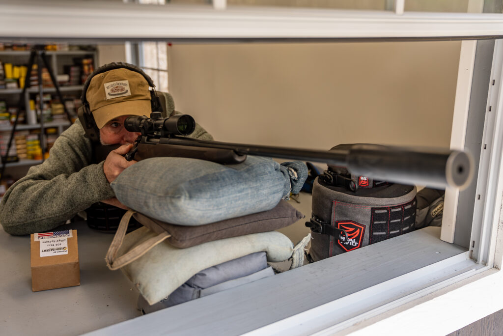 A shooter fires a Sako Grizzly rifle with suppressor attached.