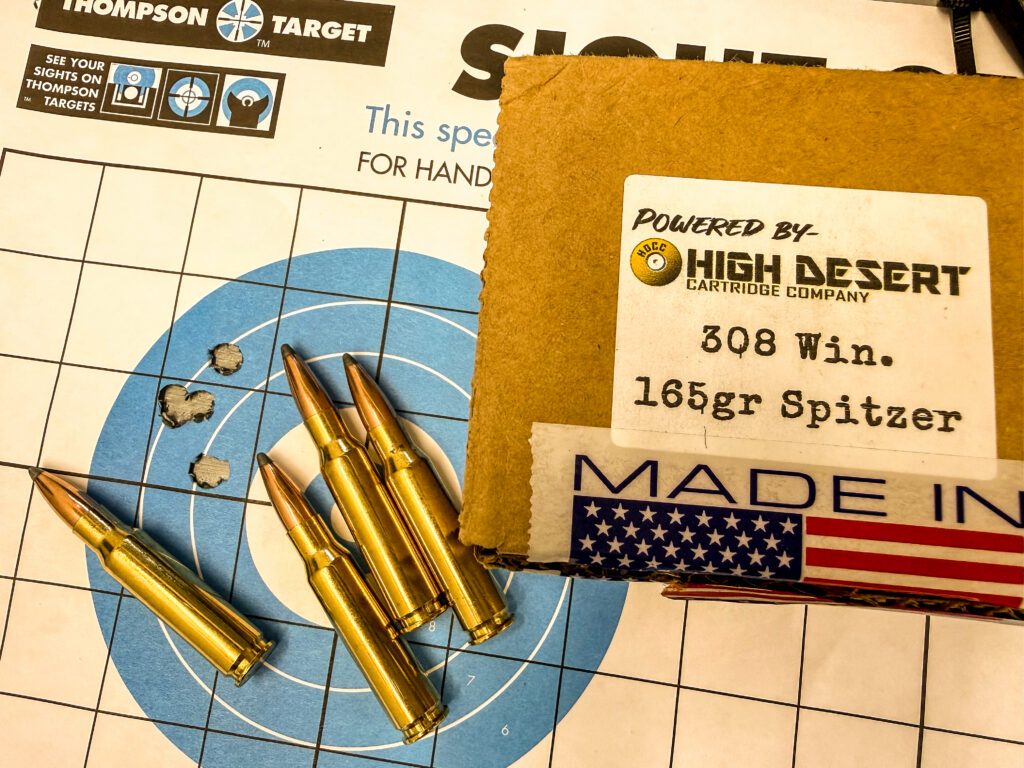 A five-shot group on a rifle target with ammo.