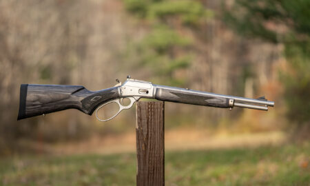 Marlin 1894 Trapper 10mm Automatic rifle balance on a post in a field.