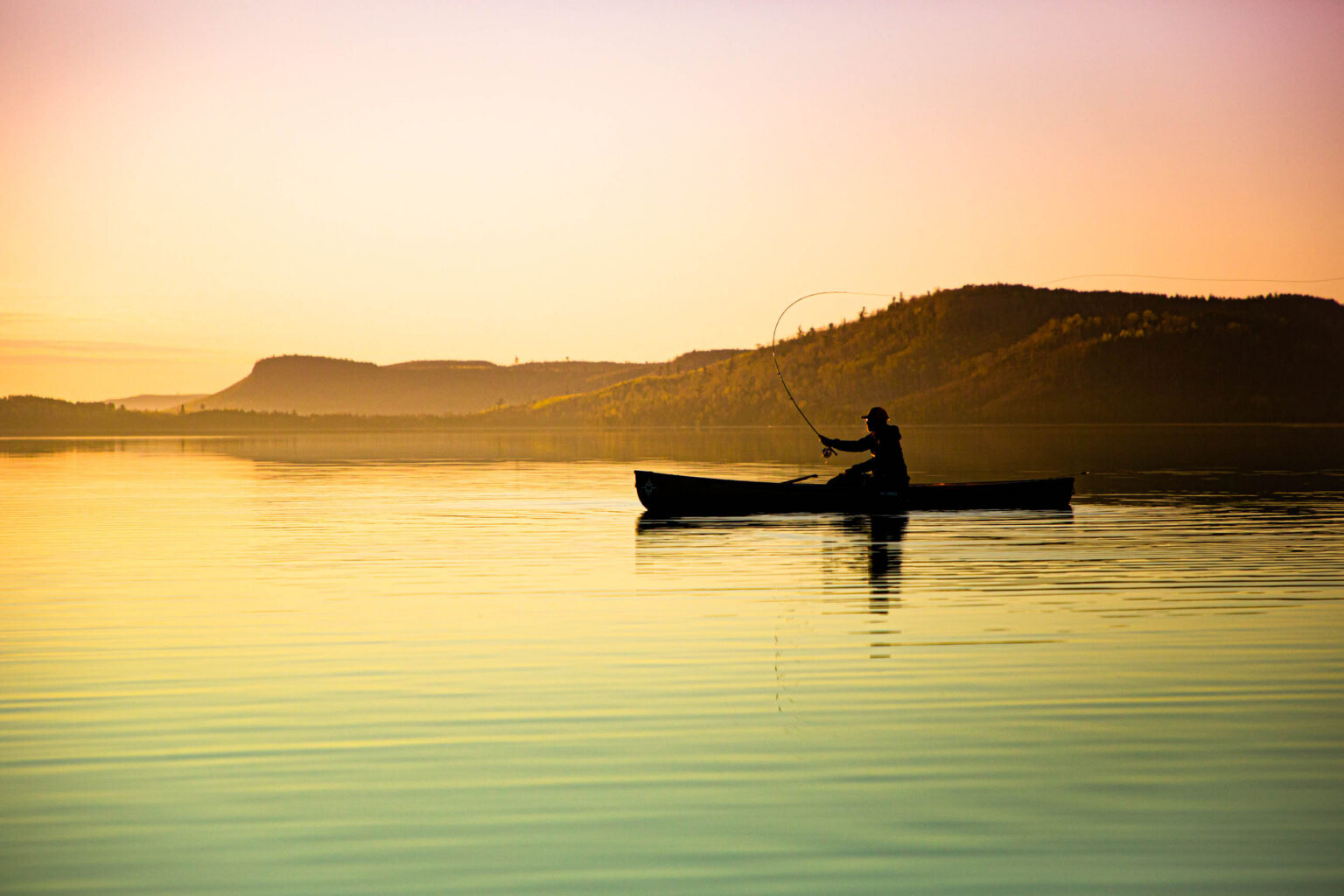 An angler fishes in the Boundary Waters at sunset.