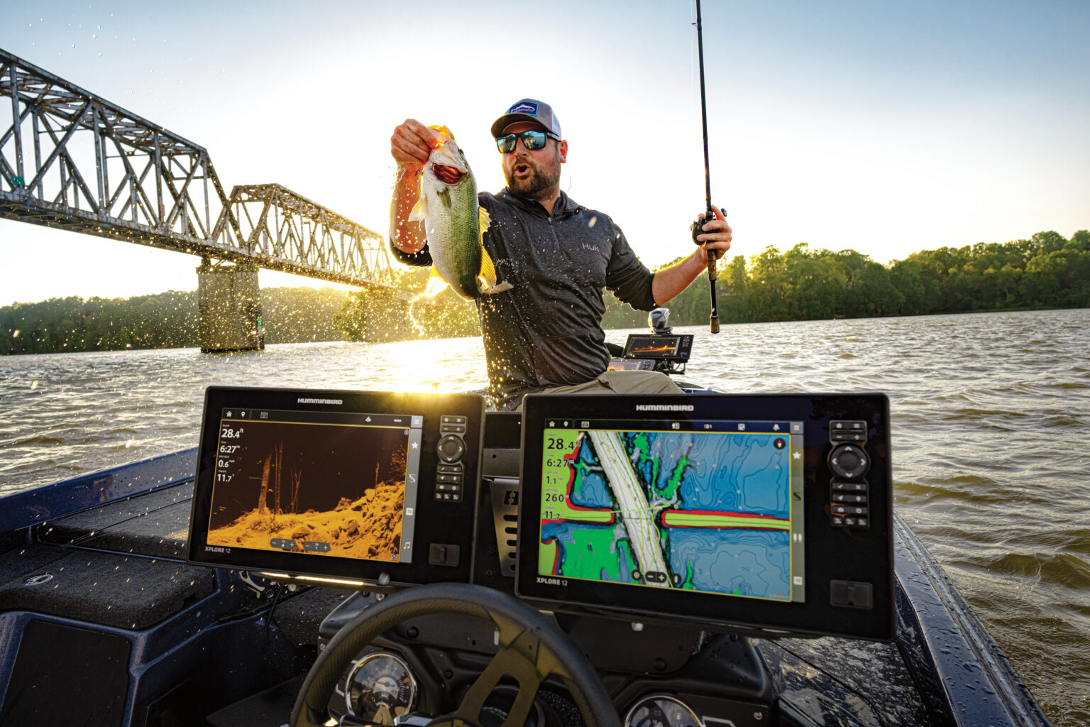 Angler holding up bass with fish finders in front