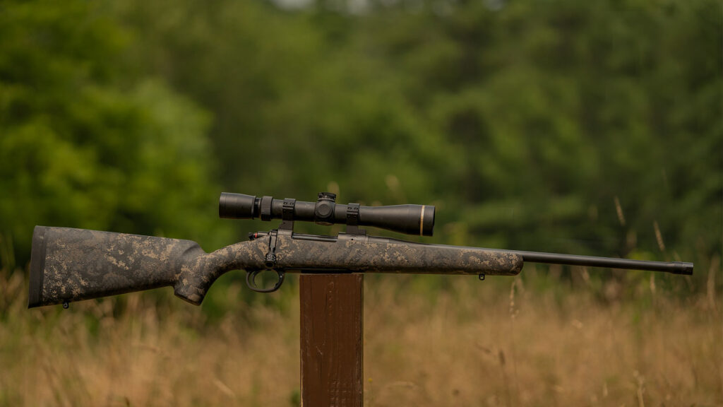 Wilson Combat NULA Model 20 rifle balanced on a post in a field. 